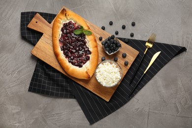 Photo of Delicious sweet cottage cheese pastry with cherry jam served on grey table, flat lay