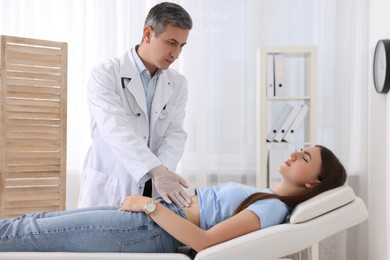 Photo of Gastroenterologist examining patient with stomach pain on couch in clinic