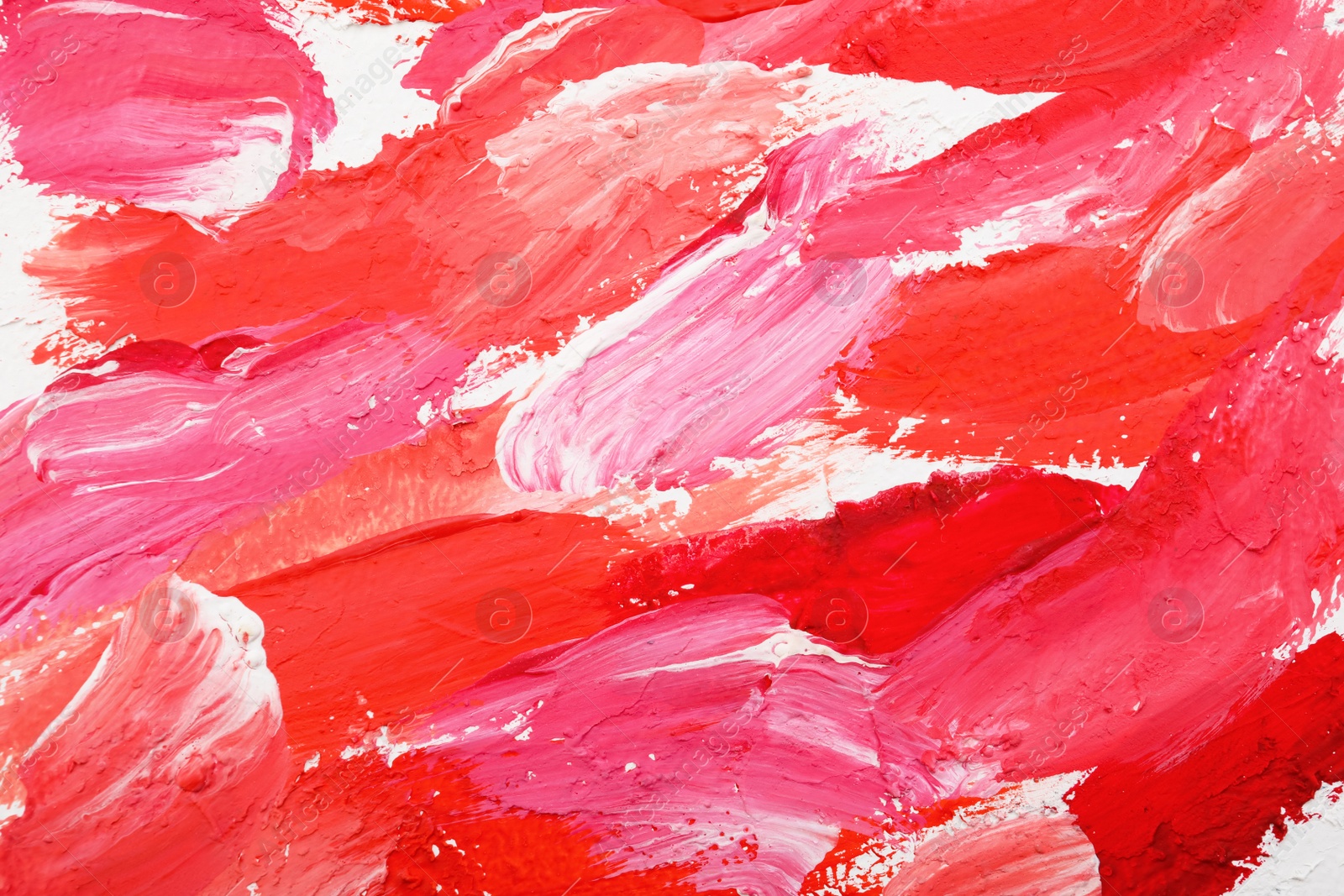 Photo of Beautiful strokes of bright oil paints on white canvas as background, closeup