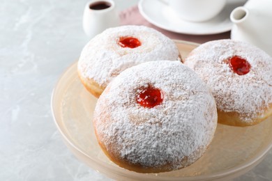 Photo of Delicious donuts with jelly and powdered sugar on pastry stand, closeup