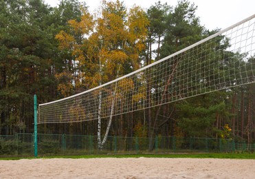 Sand volleyball court with net near trees