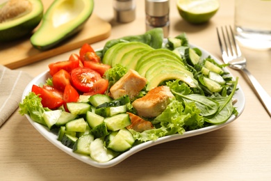 Delicious avocado salad with fried chicken on wooden table