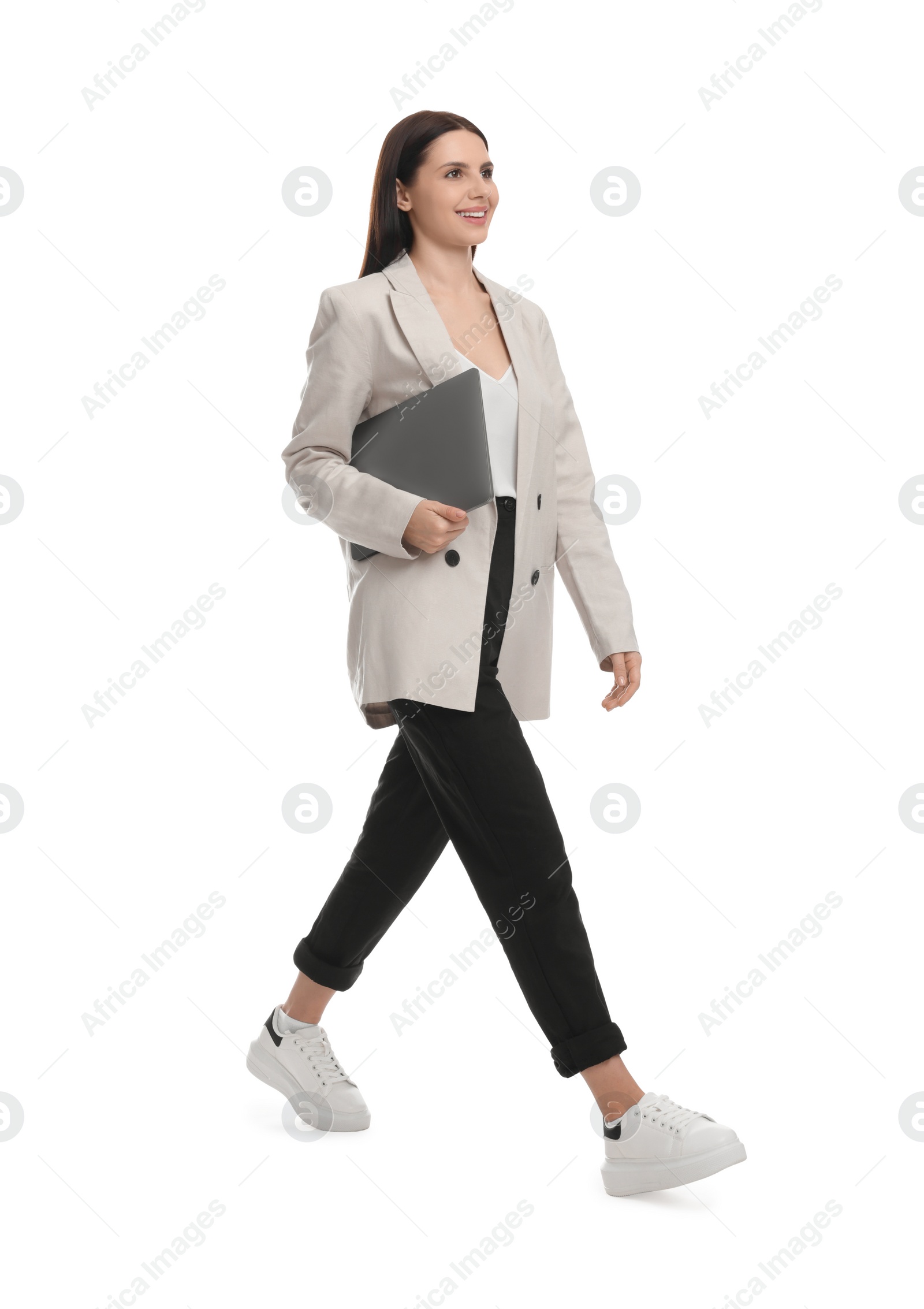 Photo of Beautiful businesswoman in suit with laptop walking on white background