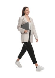 Beautiful businesswoman in suit with laptop walking on white background