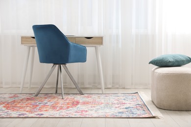 Photo of Stylish rug, armchair and table in room. Interior design