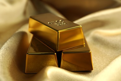 Photo of Gold bars on shiny silk fabric, closeup