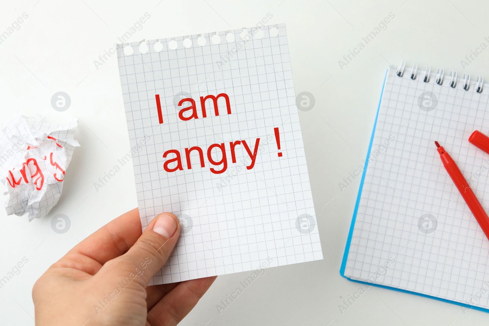 Photo of Woman holding sheet of paper with inscription I'm Angry! at white table, top view