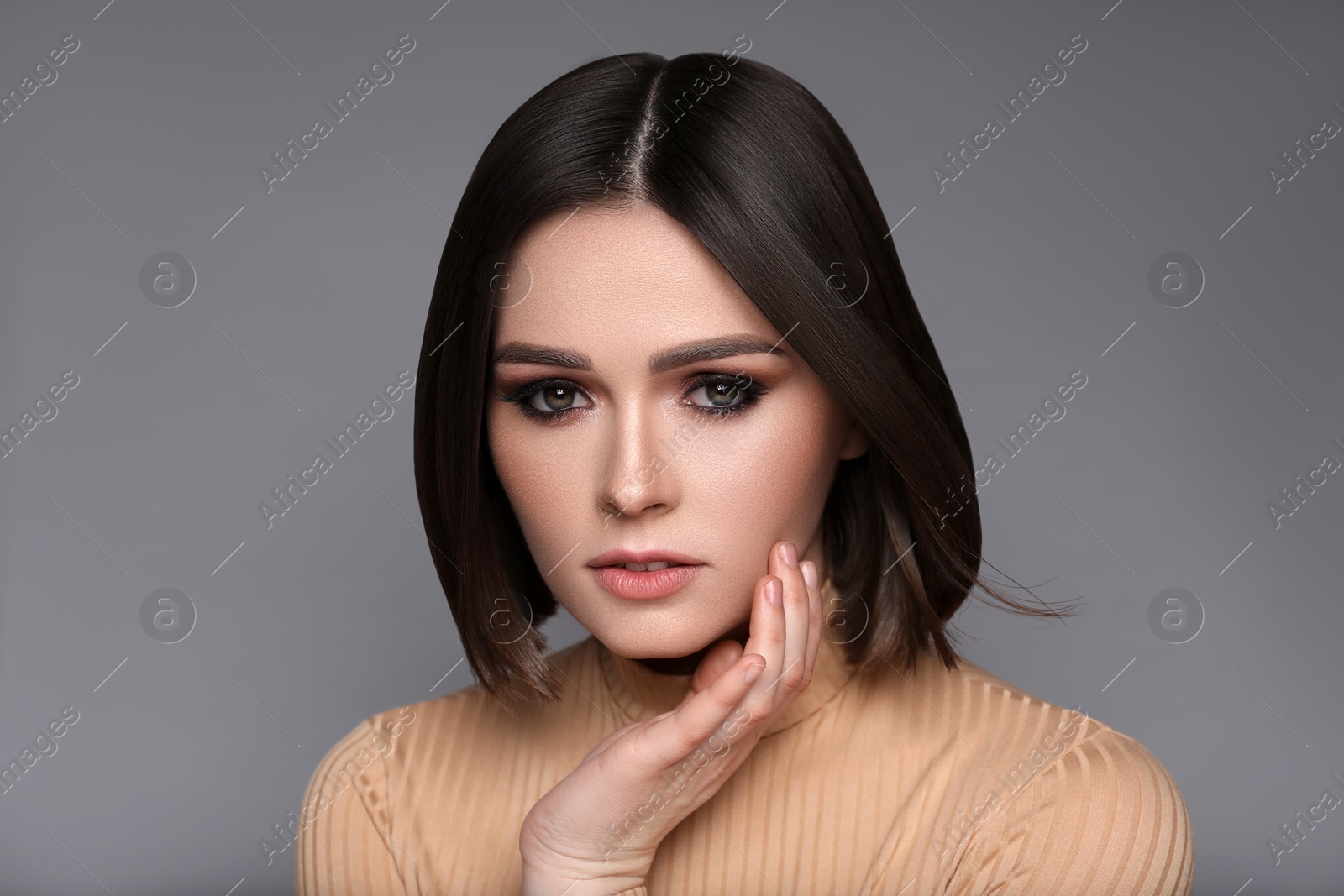 Image of Portrait of pretty young woman with brown hair on grey background