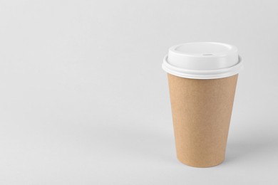 Photo of Paper cup with plastic lid on light background, space for text. Coffee to go