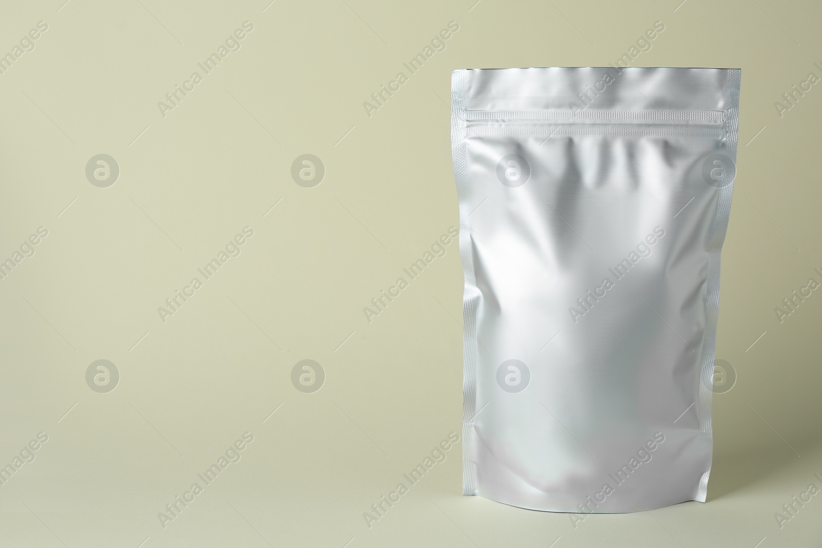 Photo of One blank foil package on beige background. Space for text