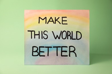 Photo of Card with text Make This World Better on pastel green background