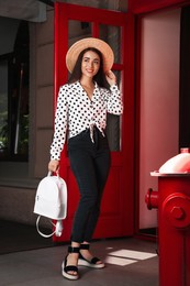 Photo of Beautiful young woman with stylish backpack and hat outdoors