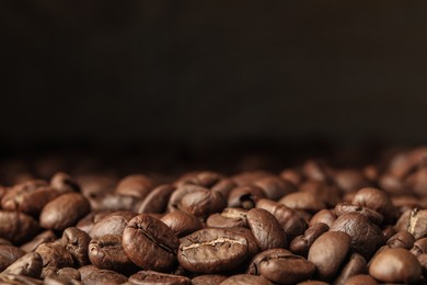 Photo of Many roasted coffee beans on dark background, closeup