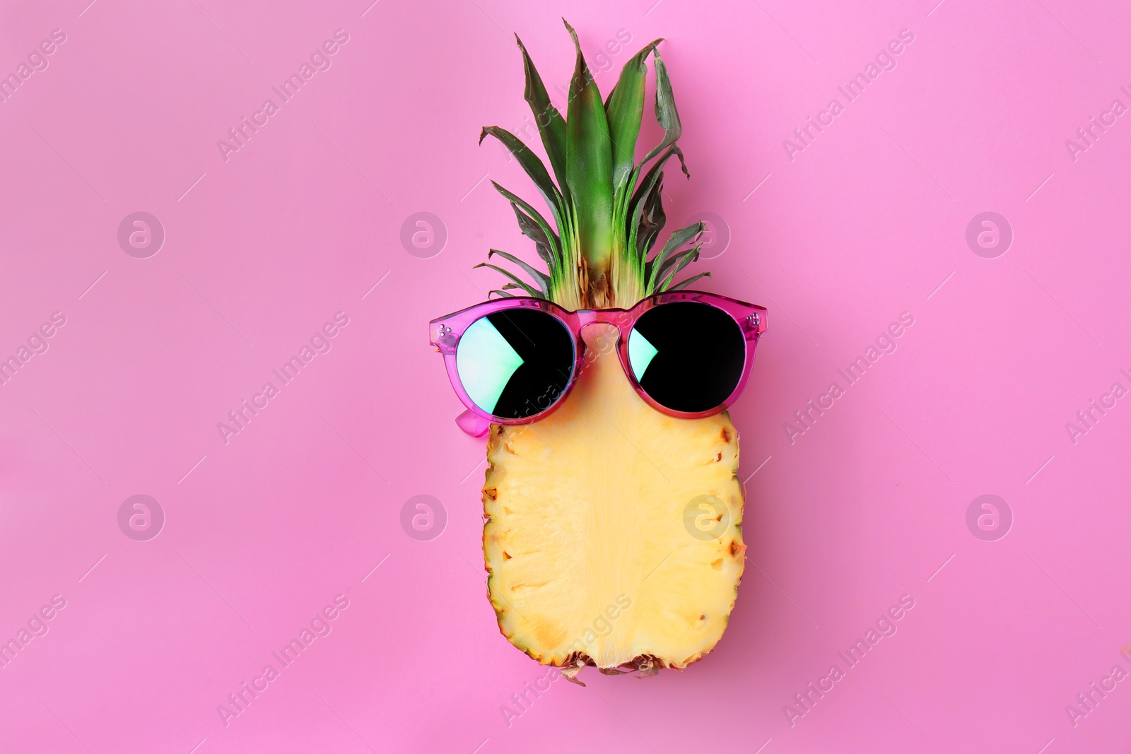 Photo of Funny pineapple with sunglasses on color background