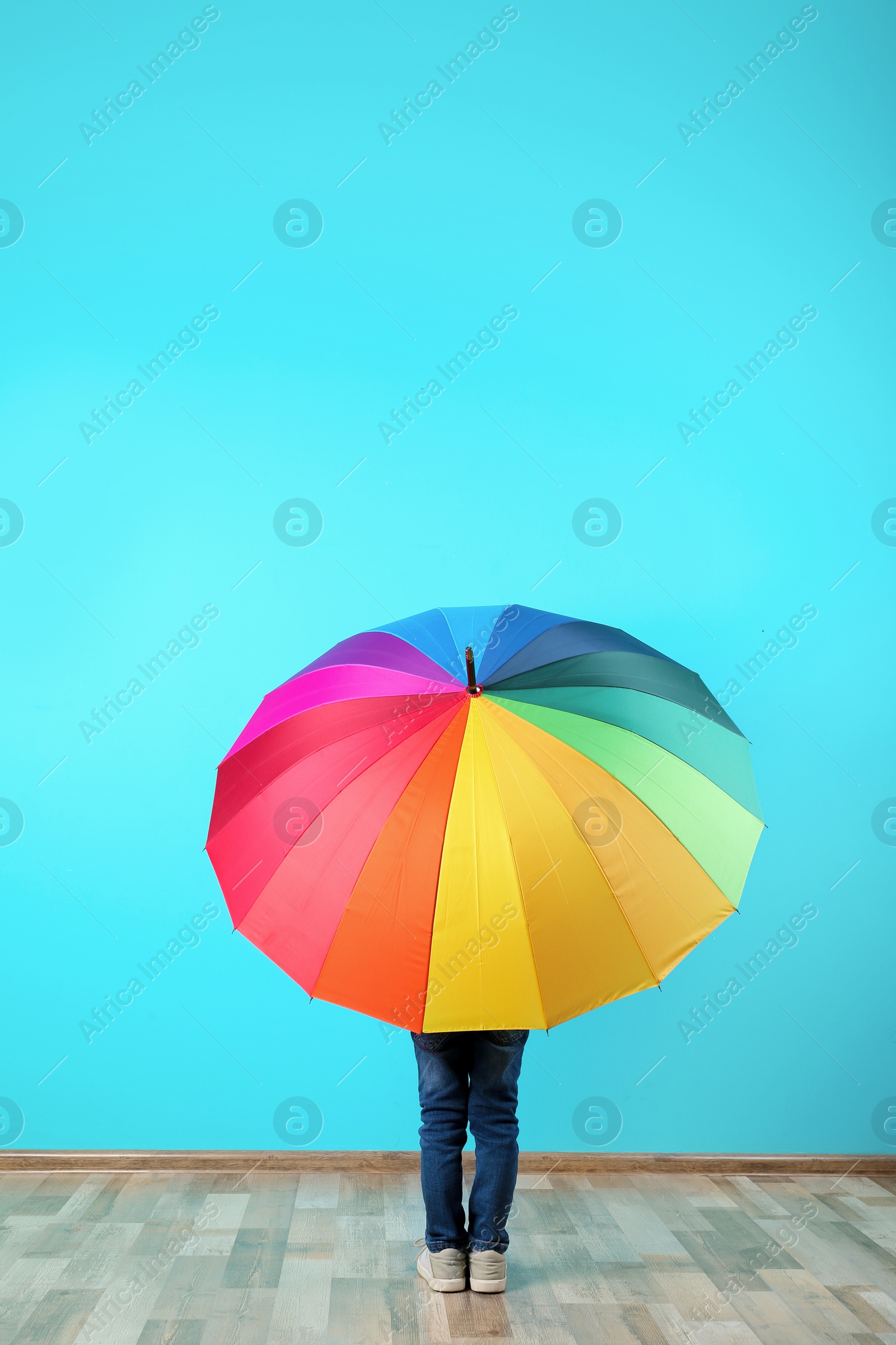 Photo of Little boy with rainbow umbrella near color wall. Space for text