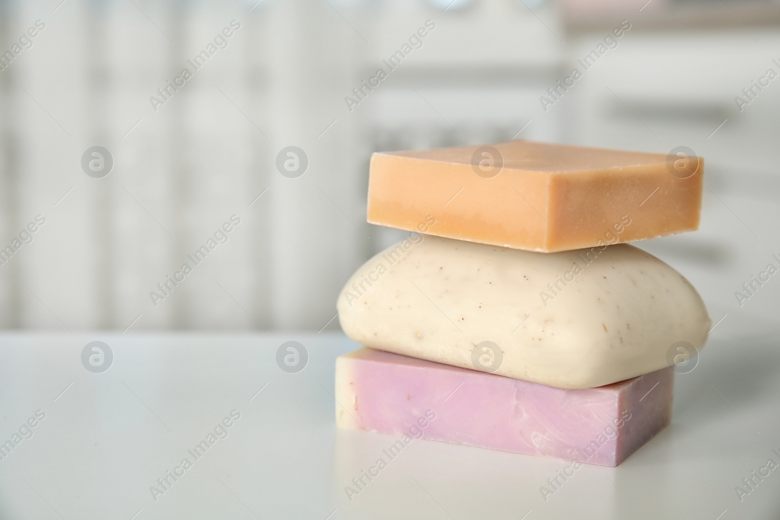 Photo of Stack of different soap bars on table. Space for text