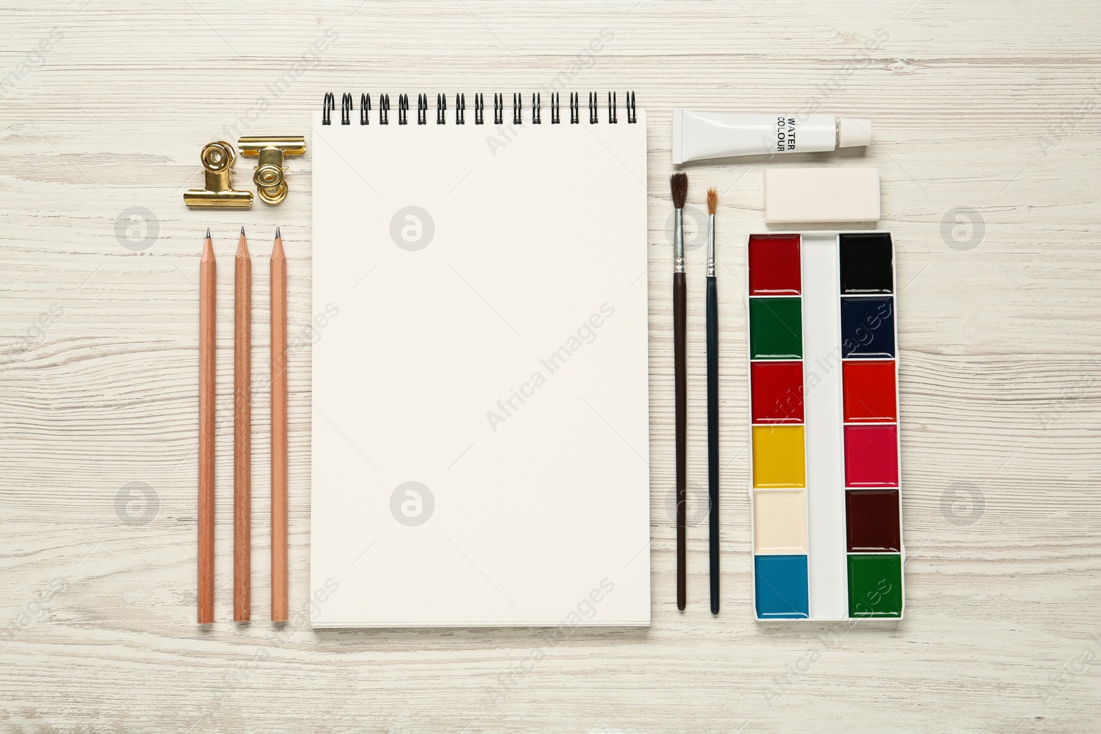 Photo of Flat lay composition with blank sketchbook on white wooden table. Space for text