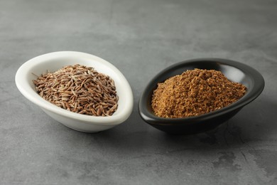 Caraway (Persian cumin) powder and dry seeds on gray table