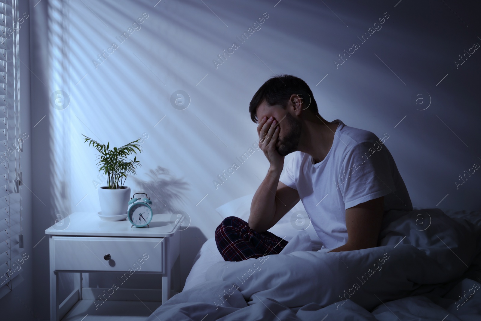 Photo of Sleepy man sitting in bed at home