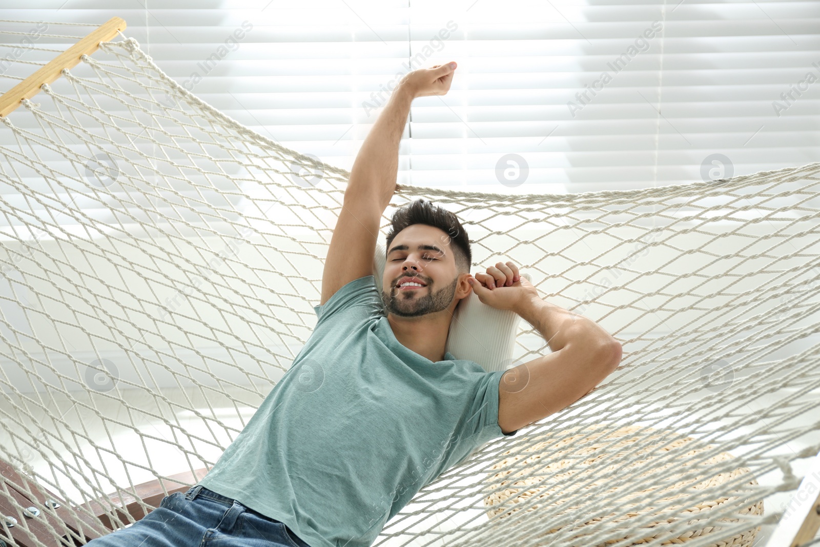 Photo of Young man relaxing in hammock at home