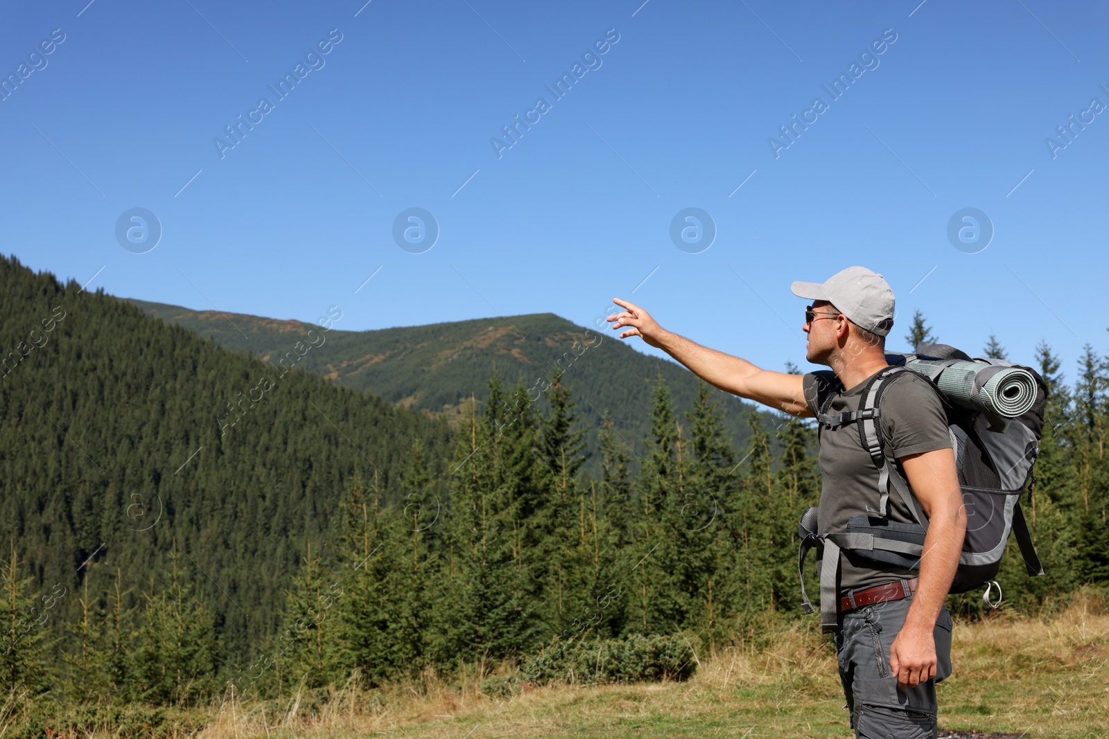 Photo of Tourist with backpack in mountains on sunny day. Space for text