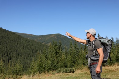 Tourist with backpack in mountains on sunny day. Space for text