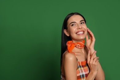 Photo of Fashionable young woman in stylish outfit with bandana on green background, space for text