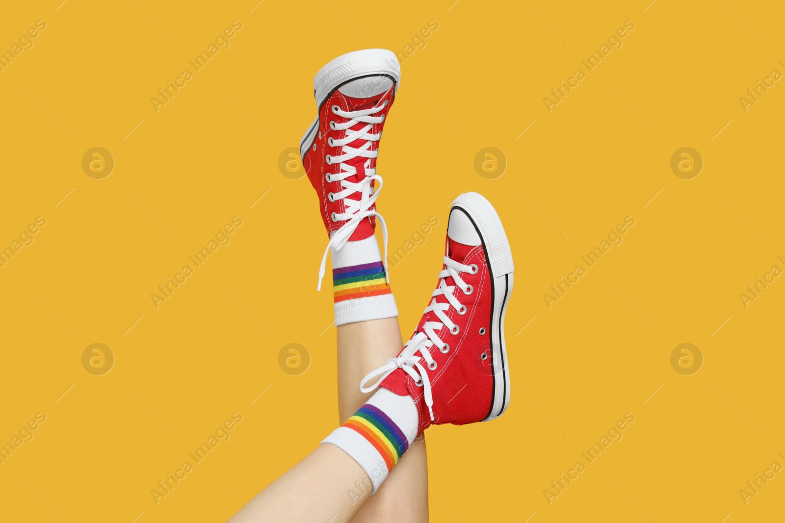 Photo of Woman in stylish gumshoes on yellow background, closeup