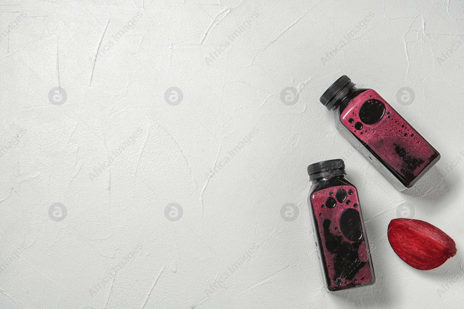 Photo of Bottles of tasty beet smoothies on light background with space for text, top view