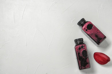 Bottles of tasty beet smoothies on light background with space for text, top view