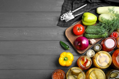 Photo of Flat lay composition with jars of pickled vegetables on grey wooden table. Space for text