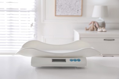 Modern digital baby scales on table in room