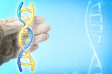 Scientist holding illustration of DNA structure in hand on light blue background, closeup
