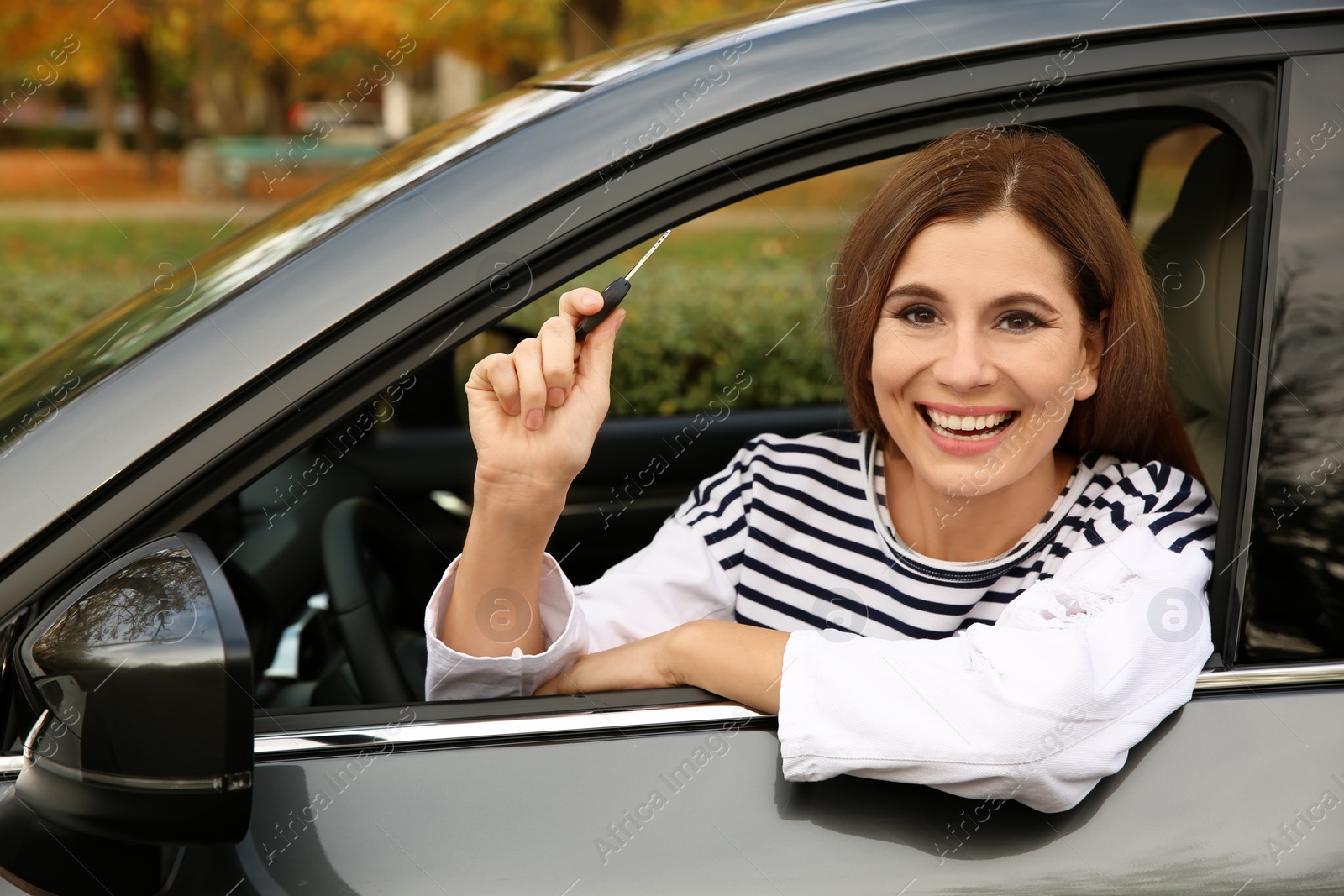 Photo of Happy woman holding car key in auto. Driving license test