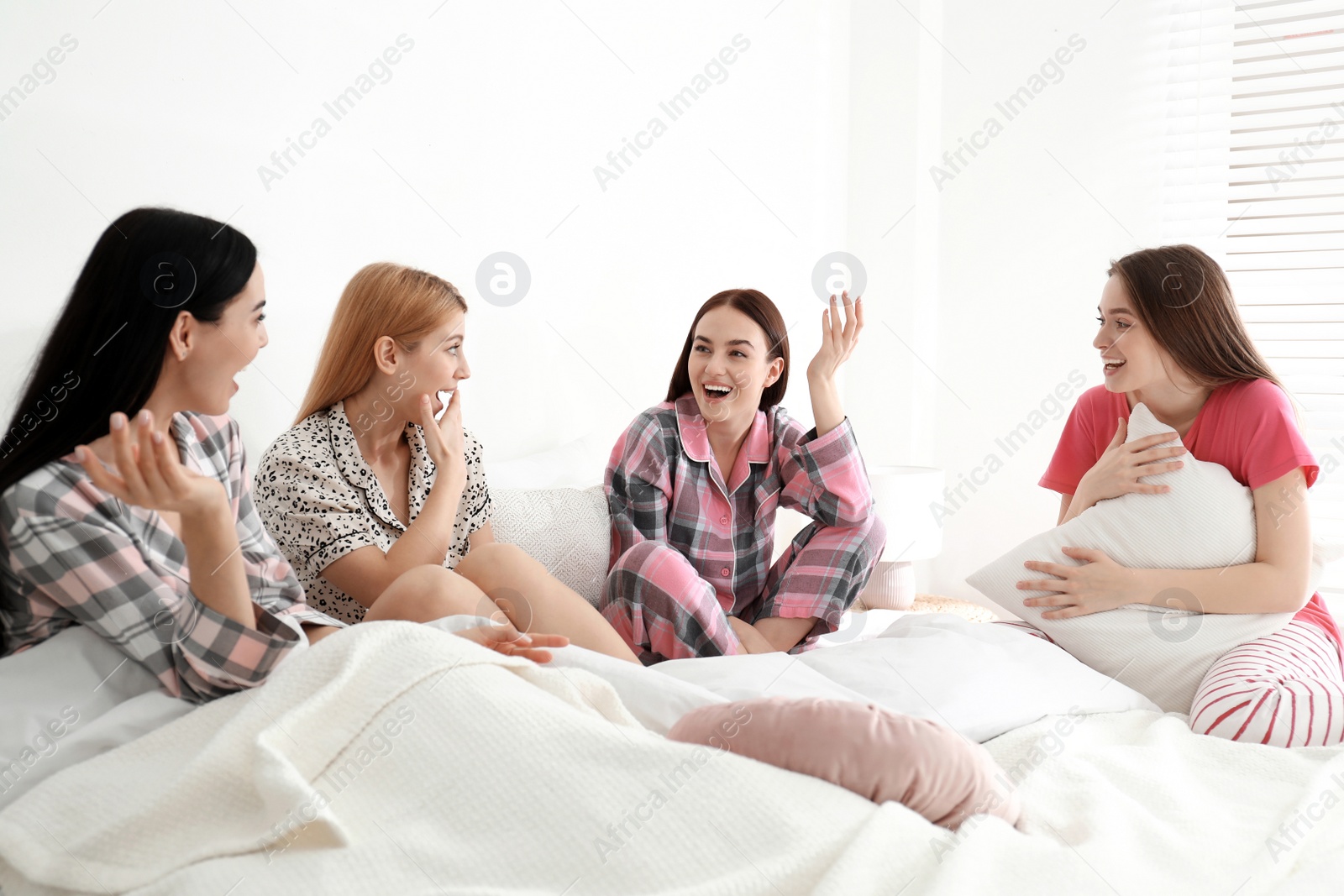 Photo of Beautiful young ladies on bed at pamper party. Women's Day