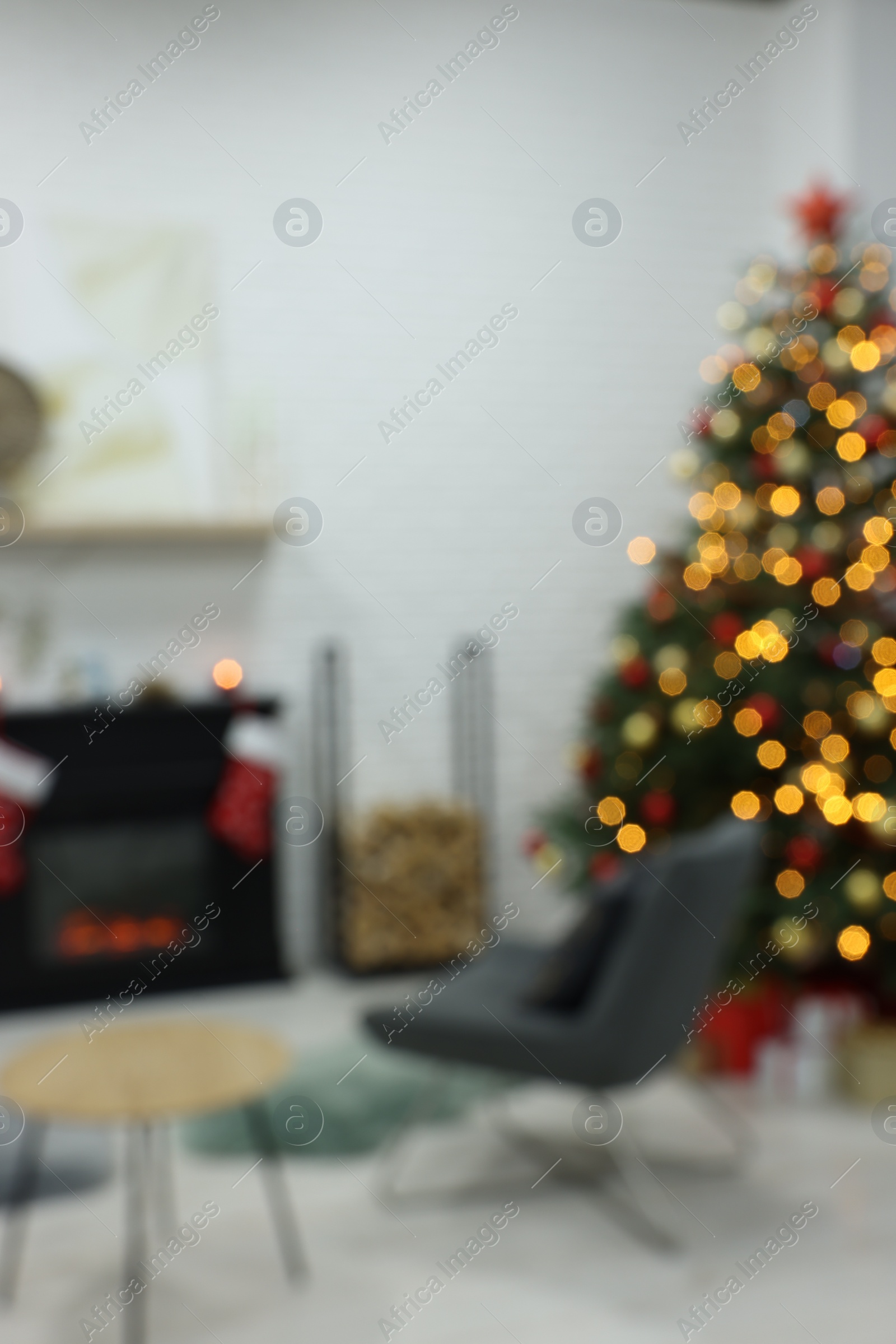 Photo of Beautiful Christmas tree near fireplace in room, blurred view