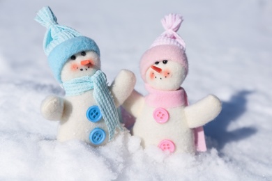 Photo of Cute small decorative snowmen on snow outdoors