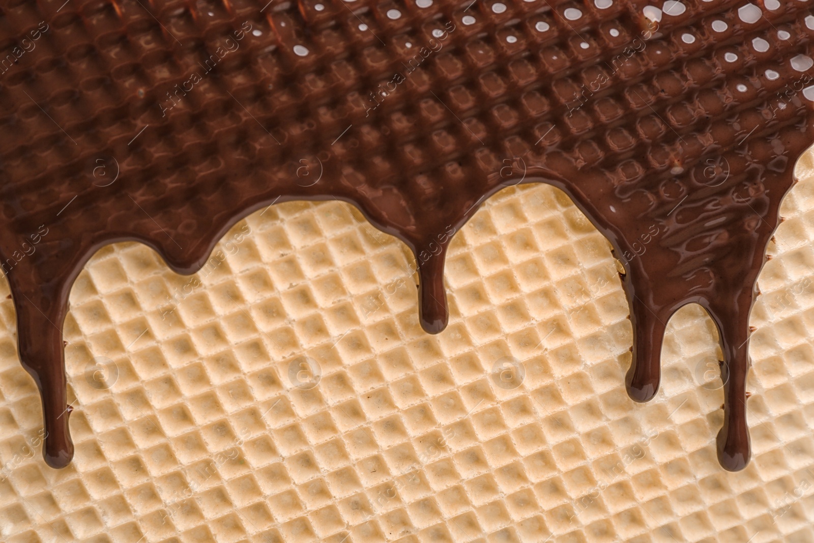 Photo of Hot dark chocolate on wafer, closeup. Crispy food