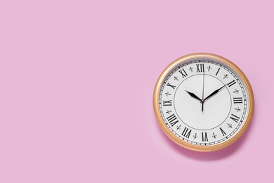 Photo of Stylish round clock on pale pink background, top view with space for text. Interior element