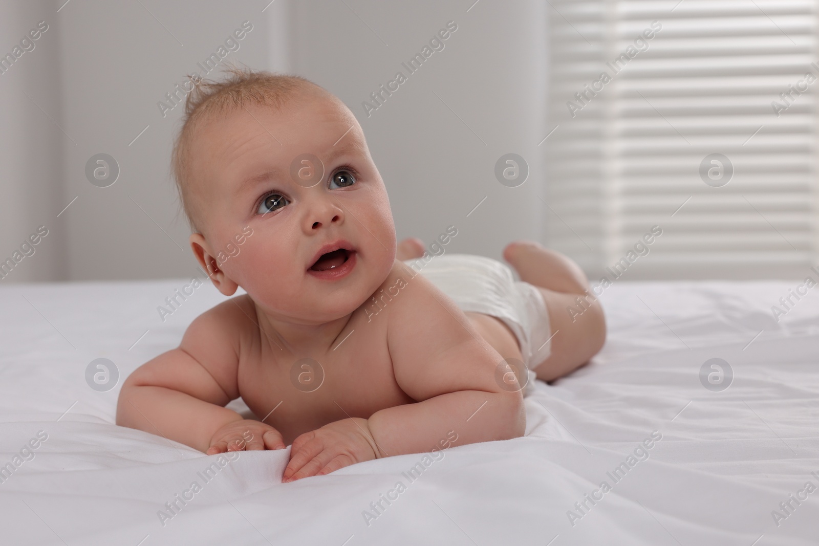 Photo of Cute little baby lying on bed in room, space for text