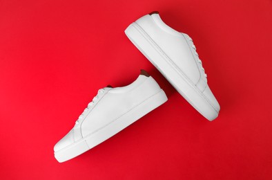 Photo of Pair of stylish sports shoes on red background, flat lay