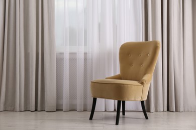 Comfortable armchair near window in room, space for text. Interior design
