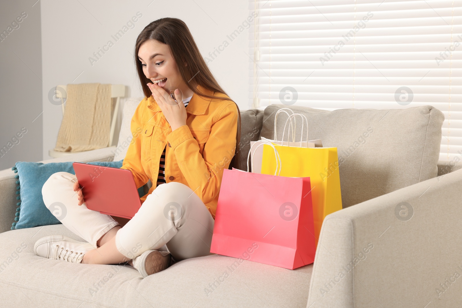 Photo of Special Promotion. Emotional woman looking at laptop on sofa indoors