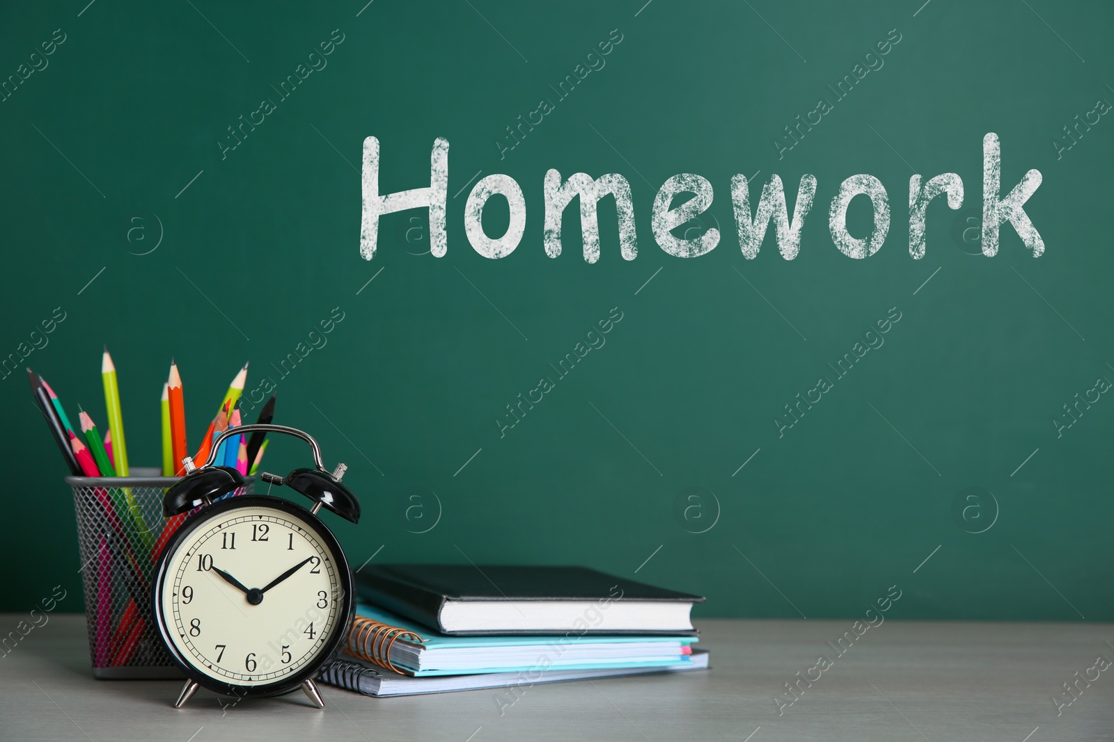 Image of Alarm clock and school stationery on white wooden table. Doing homework