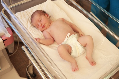 Photo of Newborn child sleeping on bed in hospital
