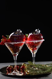 Creative presentation of Christmas Sangria cocktail in baubles and glasses on grey table against black background