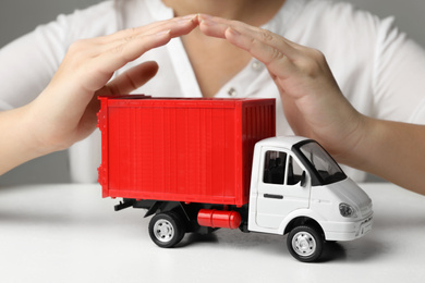Photo of Woman covering toy truck at white table, closeup. Logistics and wholesale concept