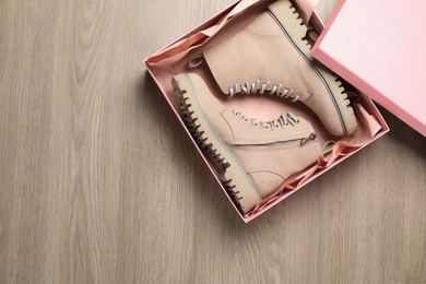 Pair of stylish boots in box on wooden background, top view. Space for text