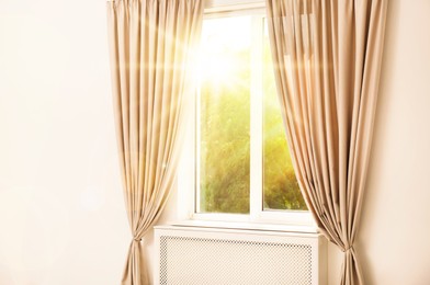 Image of Bright sun shining through window with stylish curtains