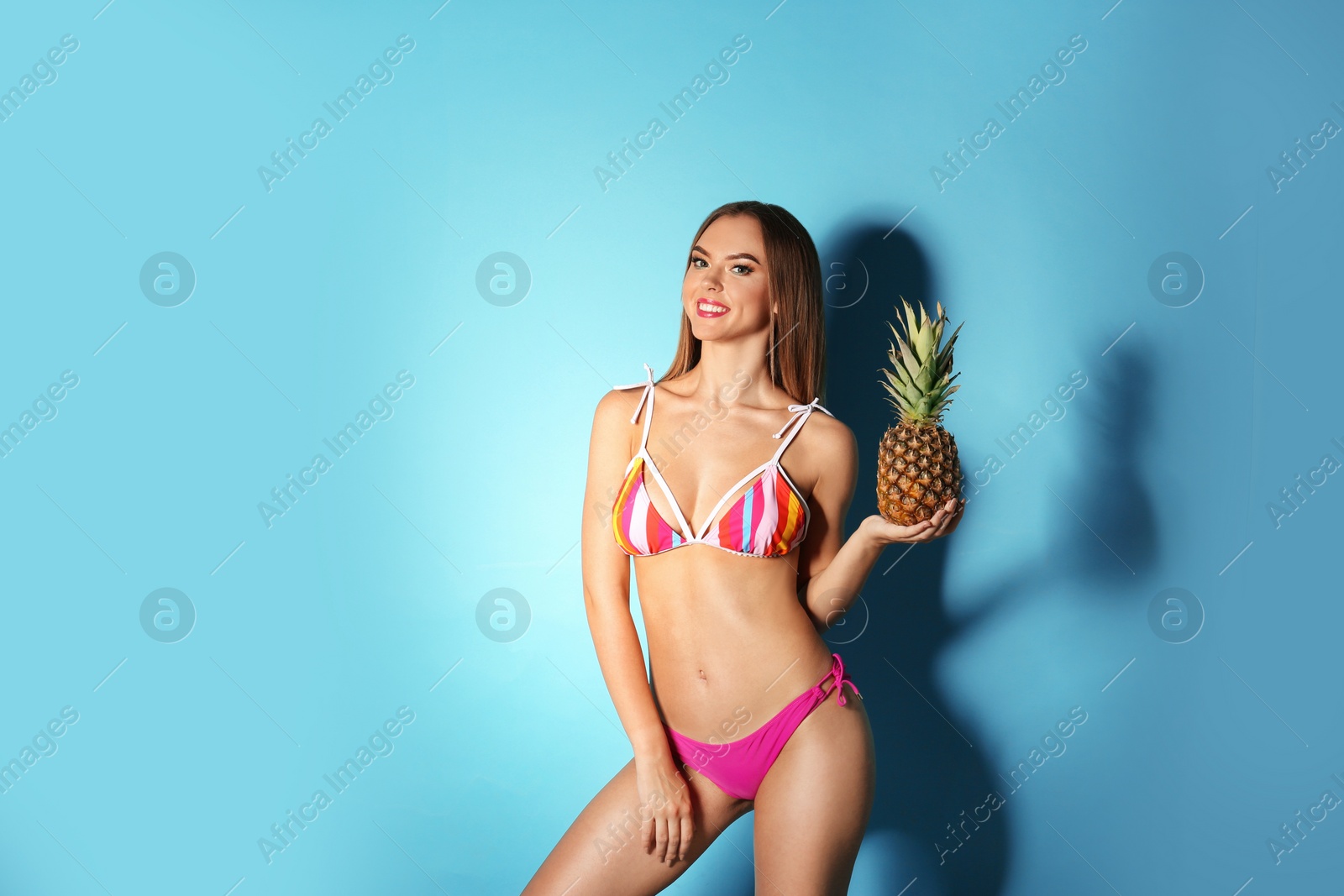 Photo of Pretty sexy woman in stylish bikini with pineapple on color background